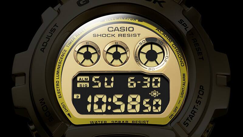 Gros plan sur l'écran d'un modèle Casio G-Shock DW-6900 doré avec affichage triple graphique réfléchissant.