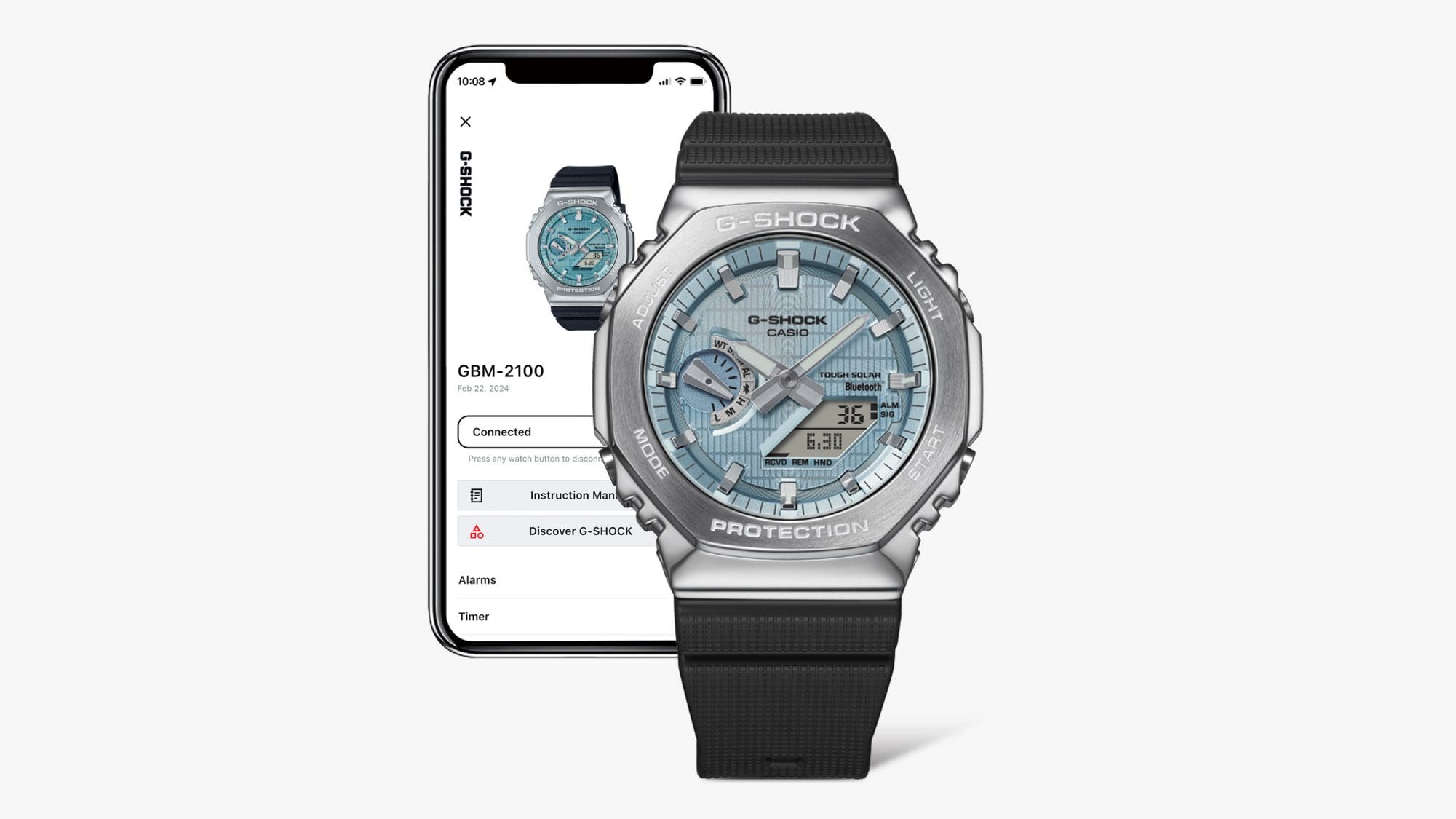 Devant : la montre solaire Casio G-Shock GBM-2100A-1A2 avec cadran bleu clair, lunette en acier inoxydable argenté et bracelet noir, derrière : un smartphone avec l'application Casio Watches.