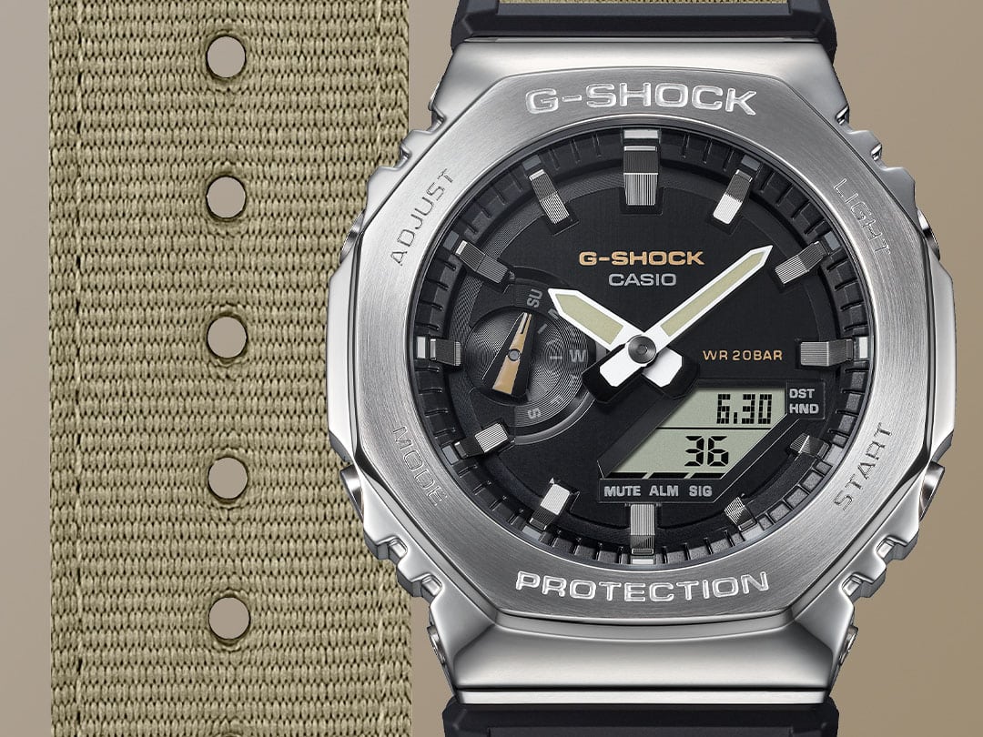 Gros plan sur le bracelet en tissu beige, le cadran noir et le boîtier en acier inoxydable argenté de la montre hybride Casio G-Shock GM-2100C-5A