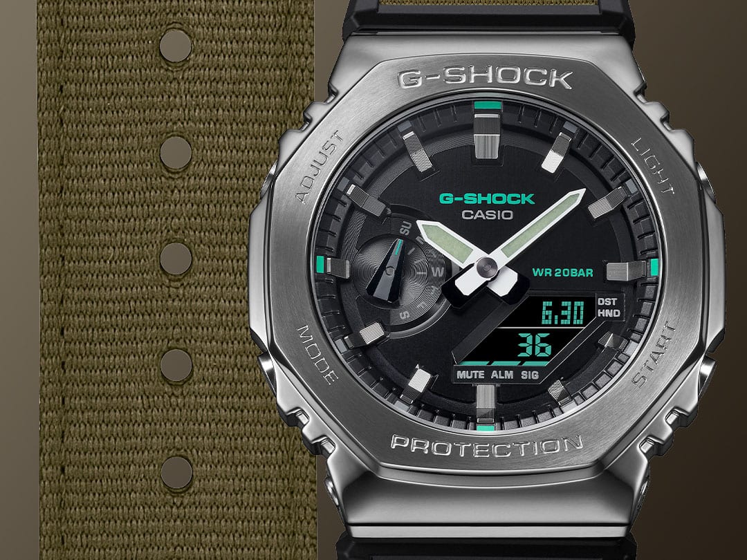Gros plan sur le bracelet en tissu de couleur olive, le cadran noir et le boîtier en acier inoxydable argenté de la montre-bracelet hybride Casio G-Shock GM-2100CB-3A