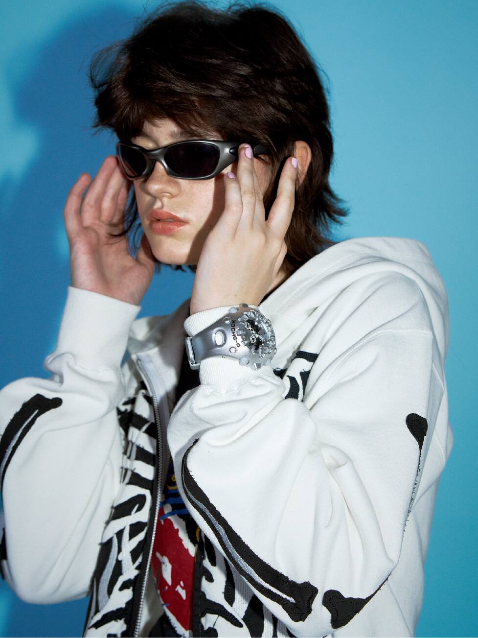 Personne portant une G-SHOCK argentée et des lunettes de soleil.
