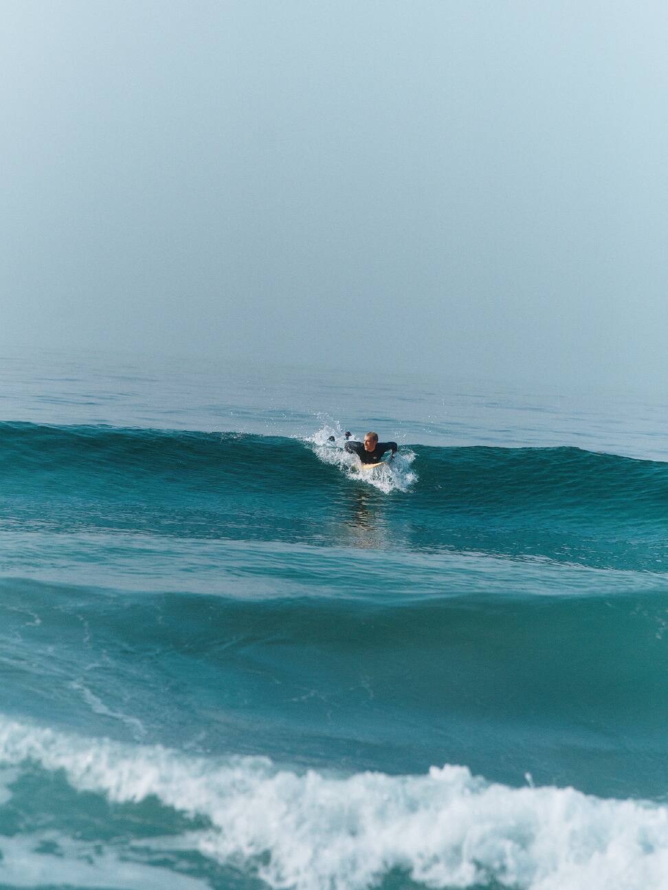 Surfeur pagayant vers une vague.