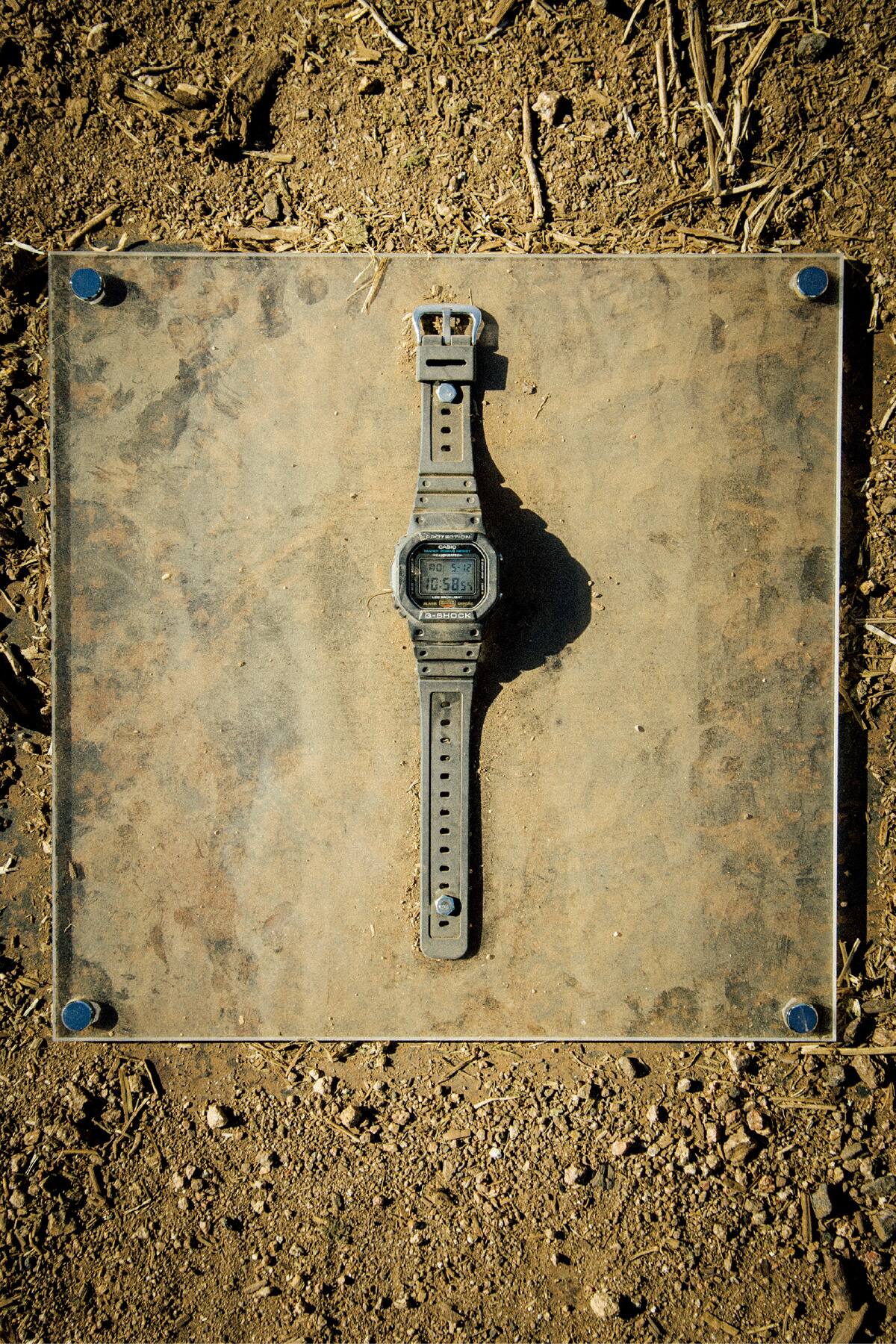 Une photo d'une G-SHOCK noire couverte de poussière après avoir été écrasée par un camion semi-remorque.