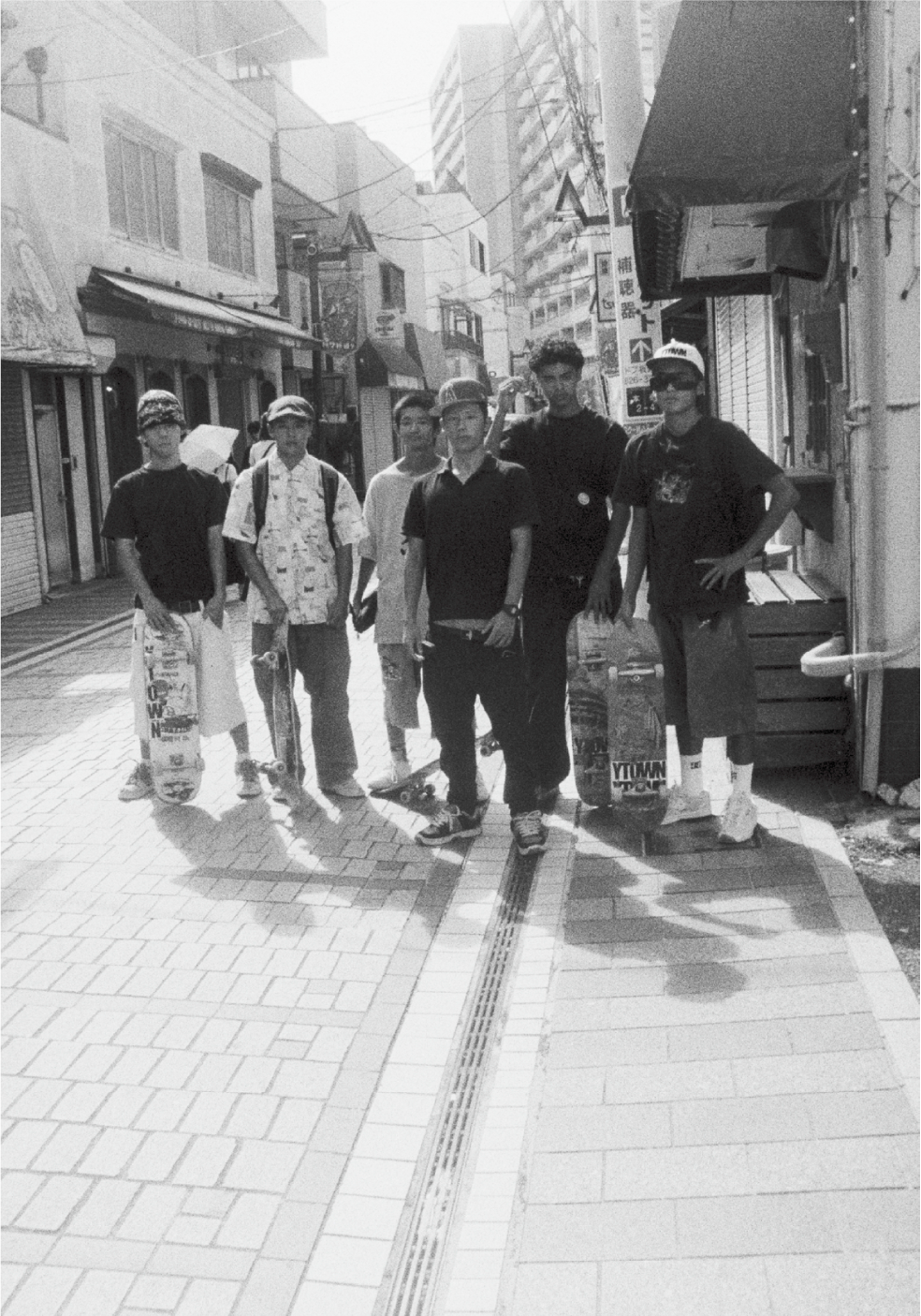 Une photographie de Yusuke Yamatani en noir et blanc qui représente un groupe de jeunes skateurs qui prennent la pose pour la photo.