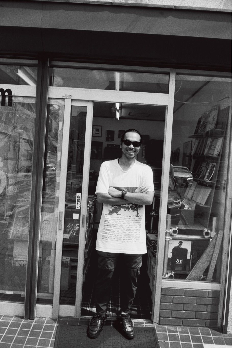Une photographie de Yusuke Yamatani qui représente le gérant d’un magasin en train de sourire devant sa boutique.