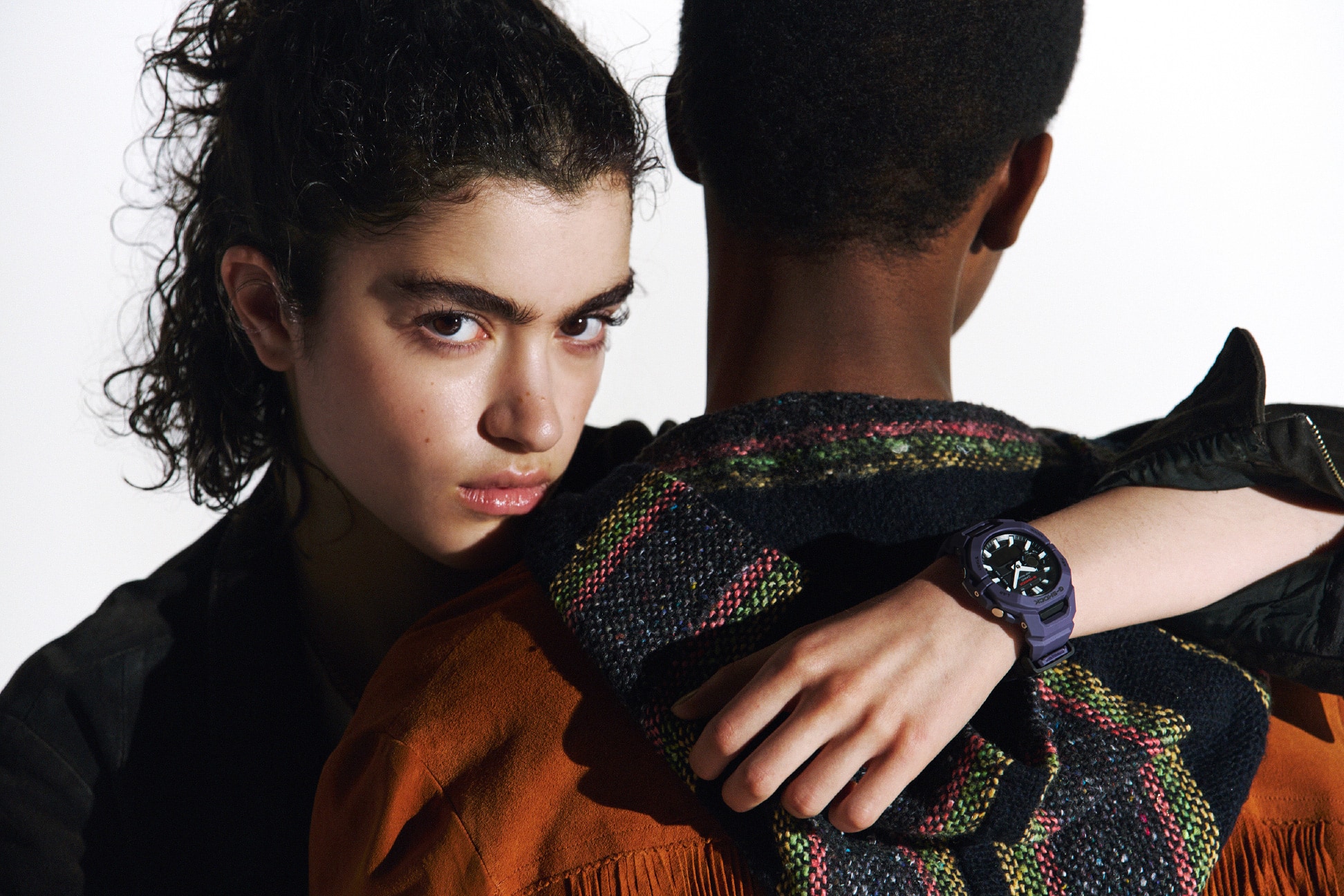 Orang yang mengenakan G-SHOCK ungu merangkul orang lain.