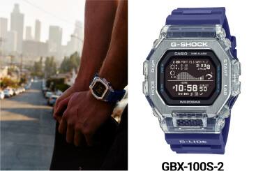 Il GBX-100 con fascia viola accanto a una persona che indossa il G-SHOCK con cassa metallica argentata e tiene in mano uno skateboard con vista sulla città di Los Angeles.