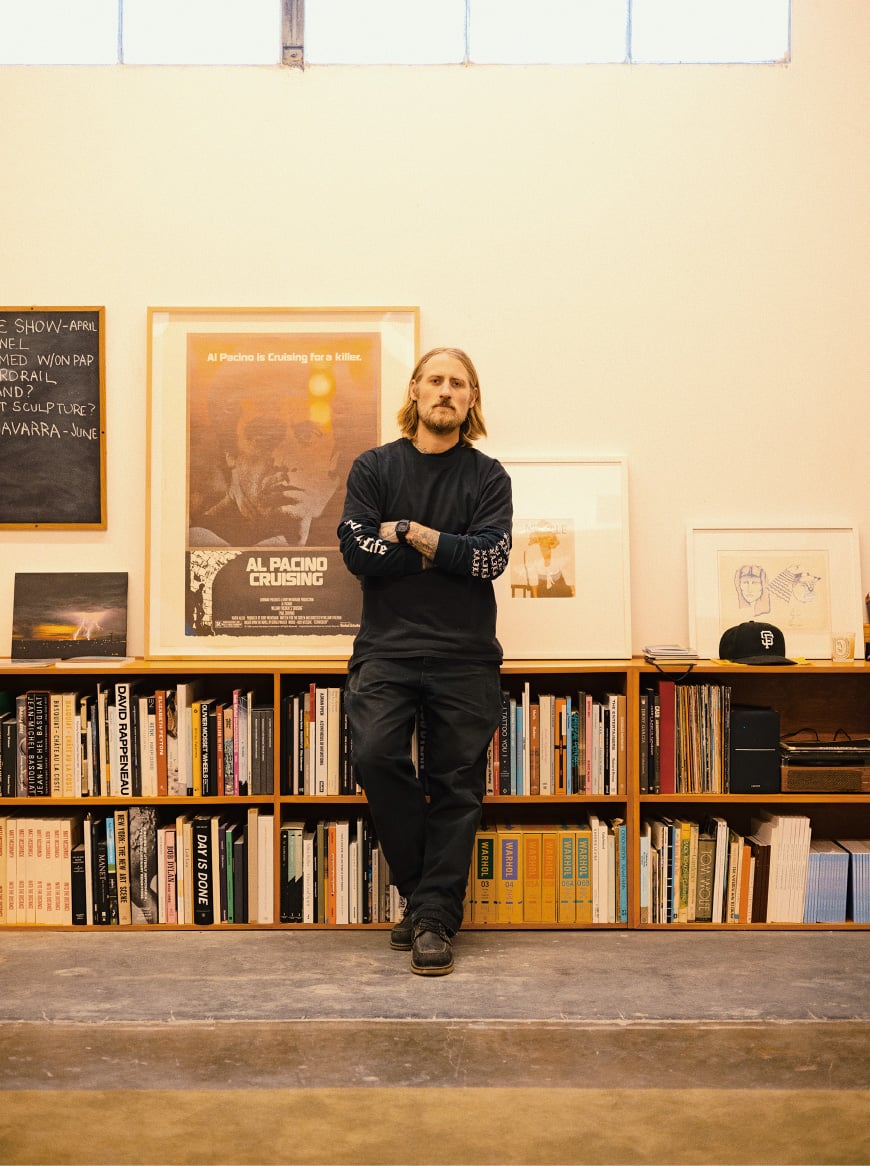 Matt McCormick è in piedi con le braccia incrociate davanti a una libreria bassa. Sullo scaffale ci sono foto incorniciate.