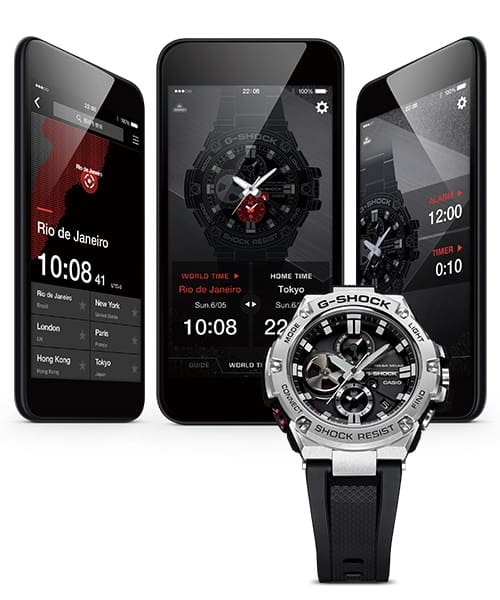 Tre smartphone con diverse schermate dell'app G-Shock Connected, di fronte a un orologio da polso Casio G-Steel GST-B100 con cinturino e quadrante neri e cassa in acciaio inossidabile color argento.