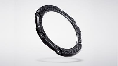 Lunetta in carbonio di un orologio da polso Casio G-Steel GST-B100 su uno sfondo grigio chiaro