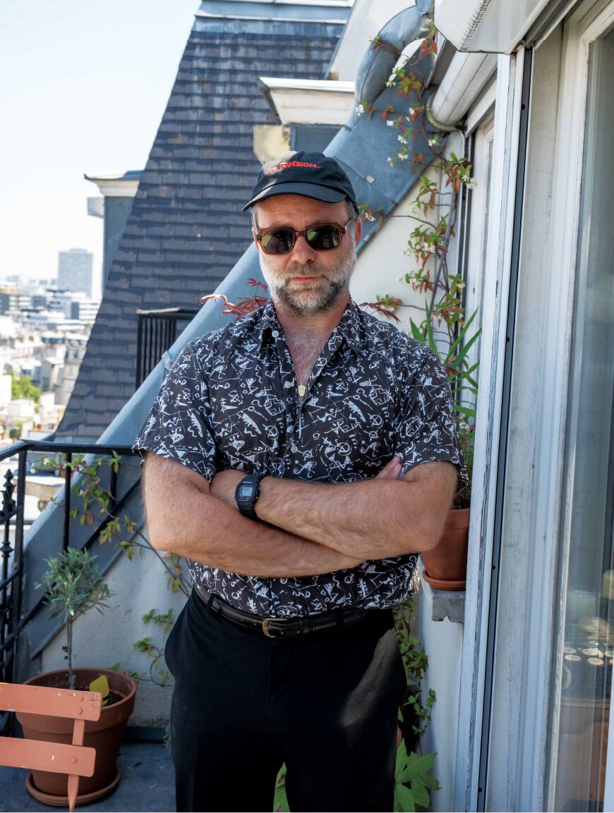 Artistiek directeur staat buiten met zwarte pet en shirt met patroon.