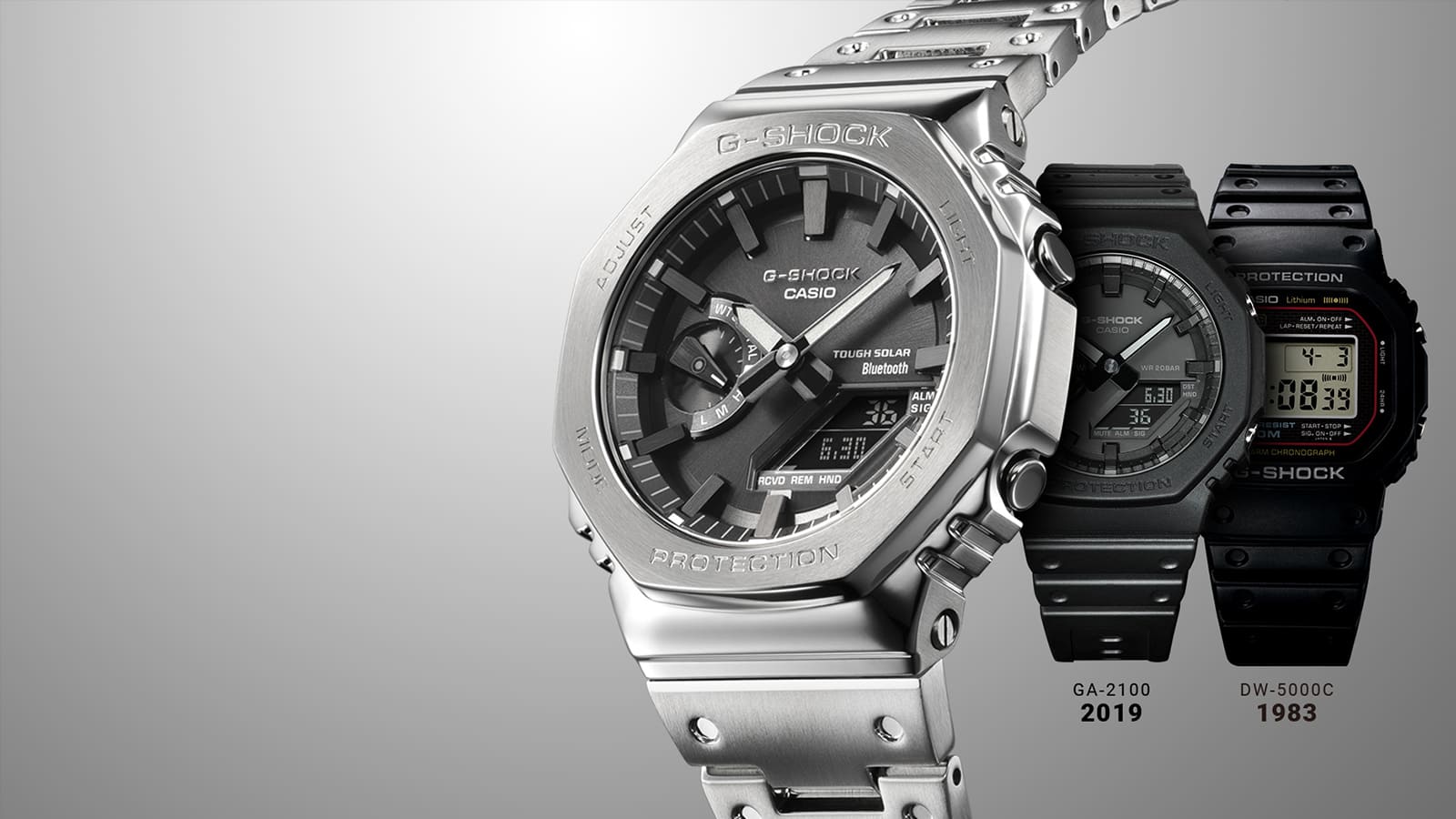 Het zilveren Casio G-Shock GM-B2100D roestvrijstalen horloge met zwarte wijzerplaat voor het zwarte GA-2100 hybride horloge uit 2019 en het zwarte DW.5000C digitale horloge uit 1983