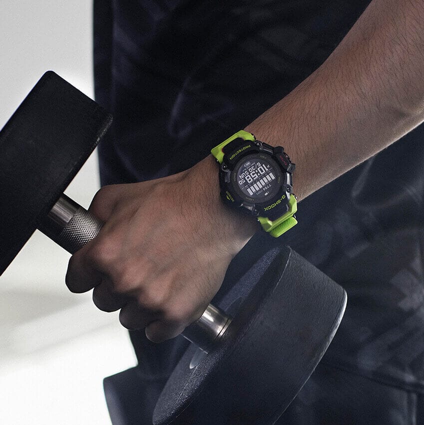 Close-up van een hand met een halter, om de pols: De Casio G-Squad GBD-H2000-1A9