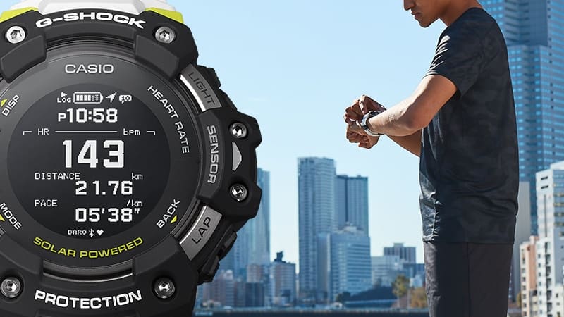Een man staat voor de skyline van een wolkenkrabber en kijkt op zijn horloge