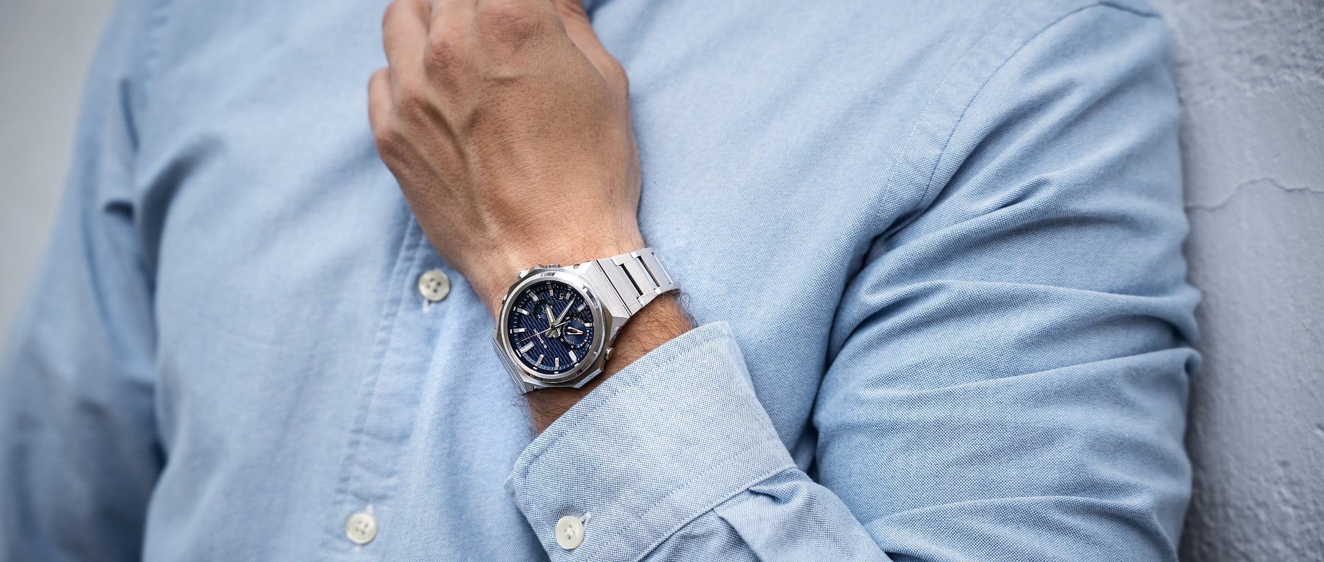 Een man in een lichtblauw overhemd draagt het G-SHOCK GST-B1000 horloge met een donkerblauwe wijzerplaat om zijn pols.