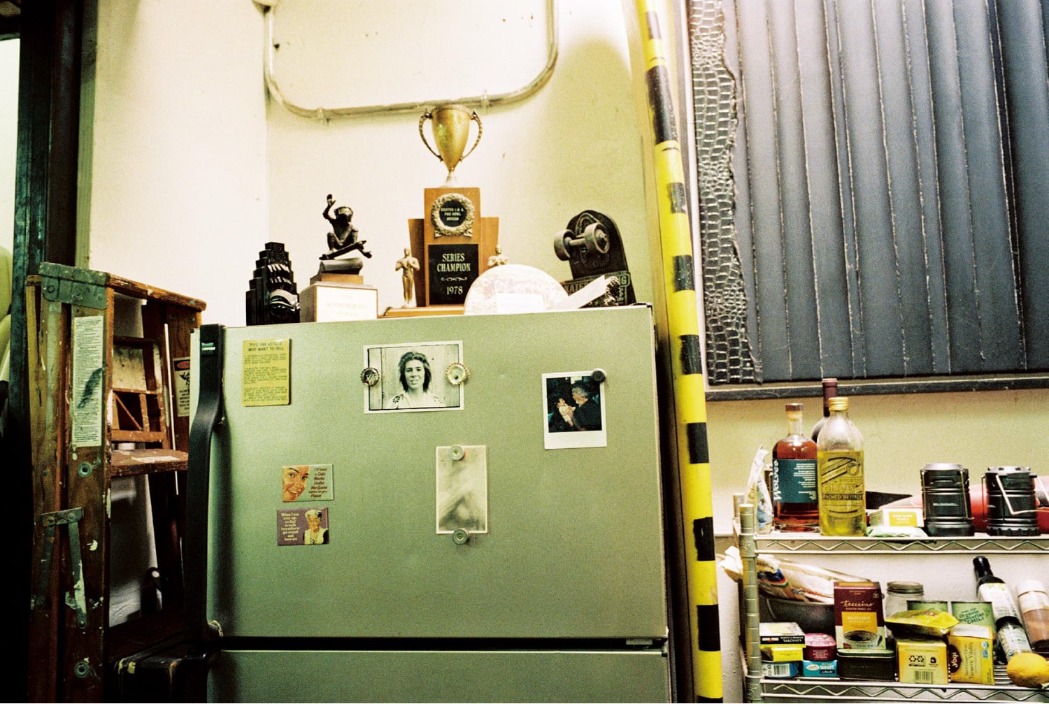 O frigorífico no escritório de Steve Olson com fotografias e ímanes. Os troféus de skate são colocados por cima.