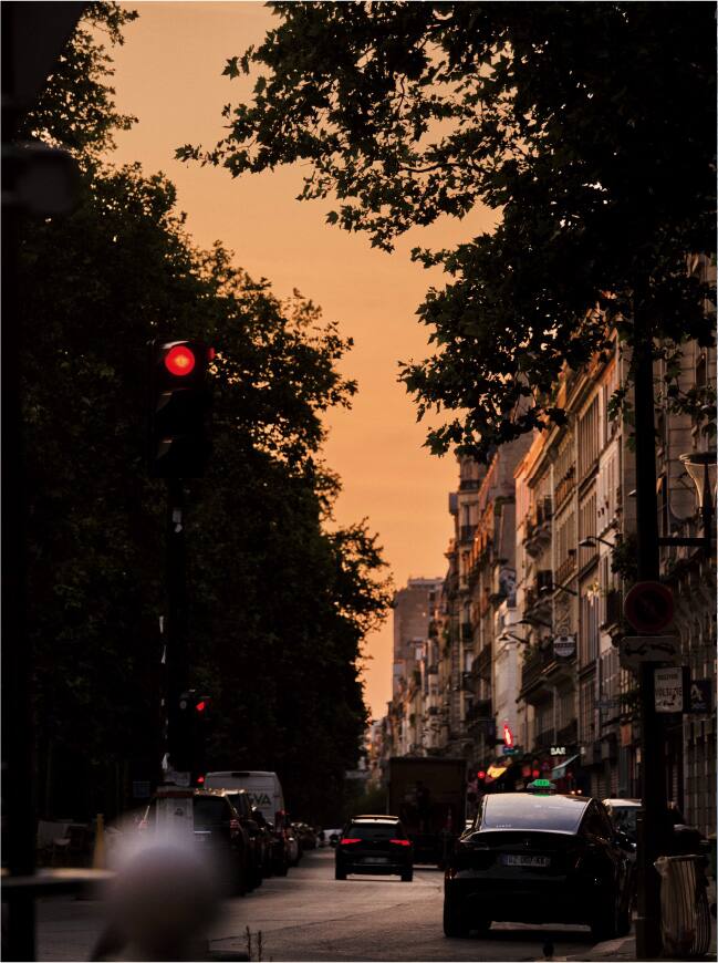 Rua da cidade ao pôr do sol com carros.