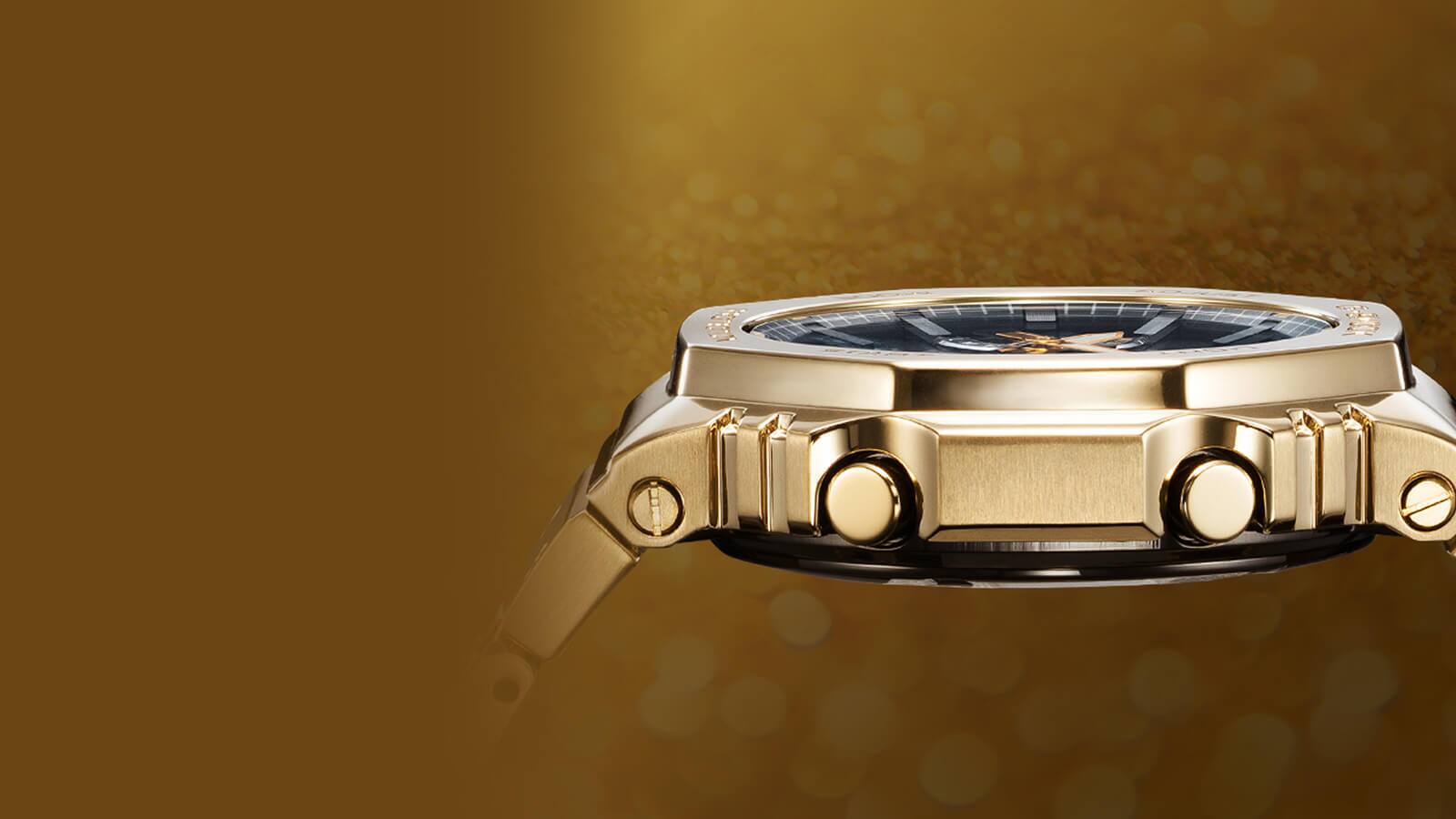  Vista lateral da caixa plana e dourada do relógio totalmente metálico Casio G-Shock GM-B2100GD com os seus botões e parafusos