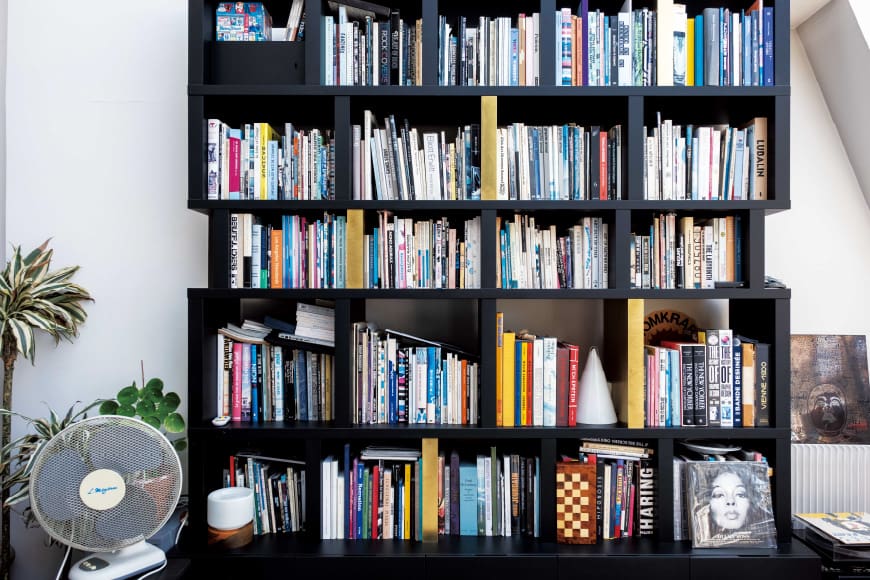 ชั้นหนังสือที่เต็มไปด้วยหนังสือศิลปะและการออกแบบในพื้นที่สตูดิโอ