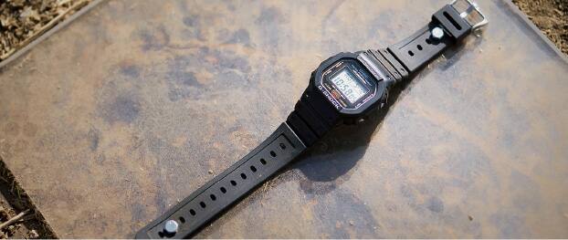Yere yerleştirilmiş siyah bir G-SHOCK saatin fotoğrafı.