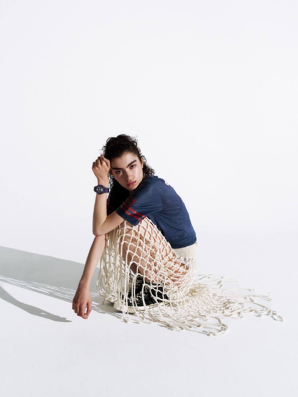 一個人戴著紫色 G-SHOCK 身穿網狀短裙坐著拍照。