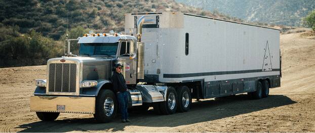 半掛式貨車停泊於寬闊未鋪裝道路的相片。